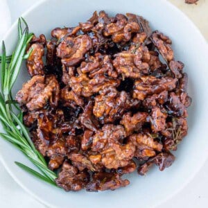 completed sweet rosemary walnuts plated on a white plate against a white surface