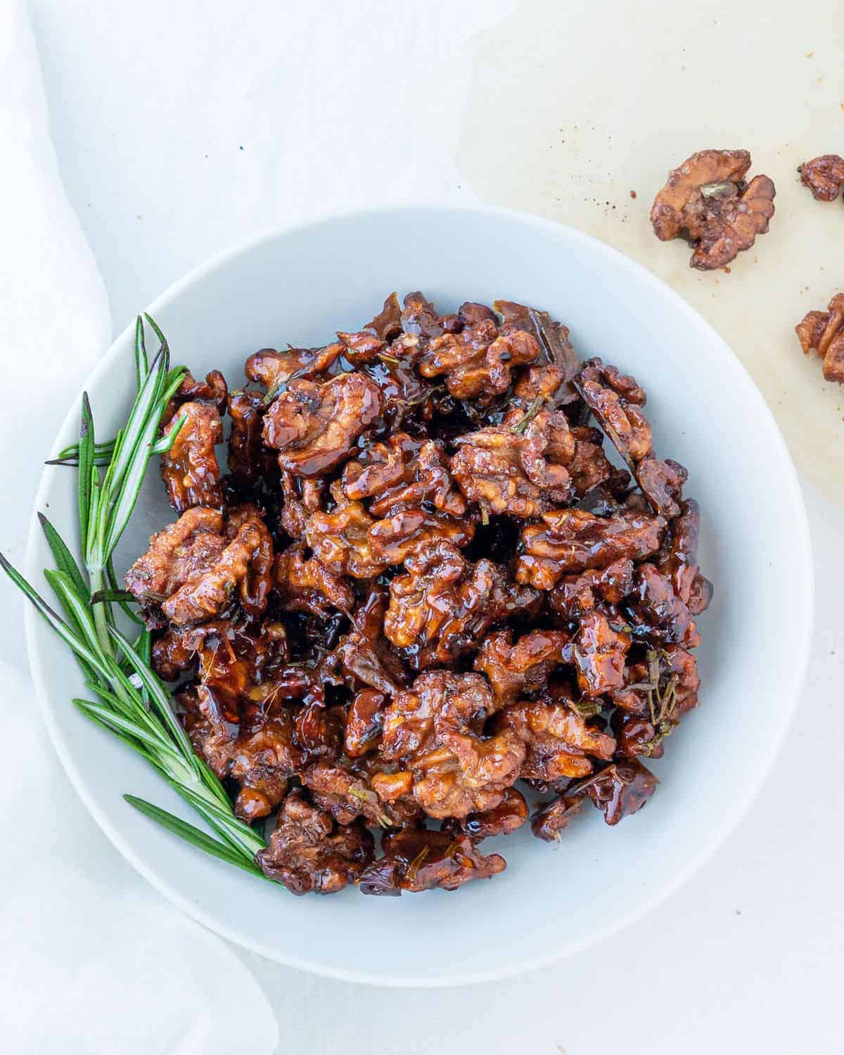 completed sweet rosemary walnuts plated on a white plate against a white surface