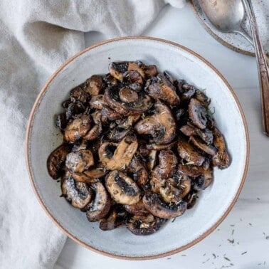 completed simple roasted mushrooms on a white plate against a white background