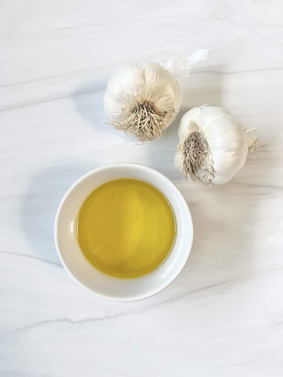 ingredients for Stovetop Roasted Garlic against a white marble surface