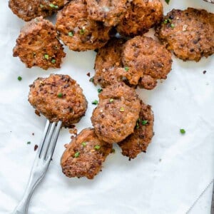 completed Quinoa Tater Tots on a white surface with a fork and sauce on the side