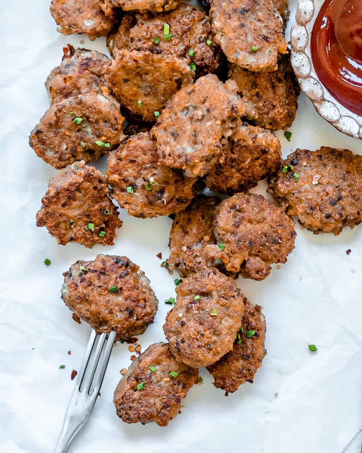 completed Quinoa Tater Tots on a white surface with a fork and sauce on the side