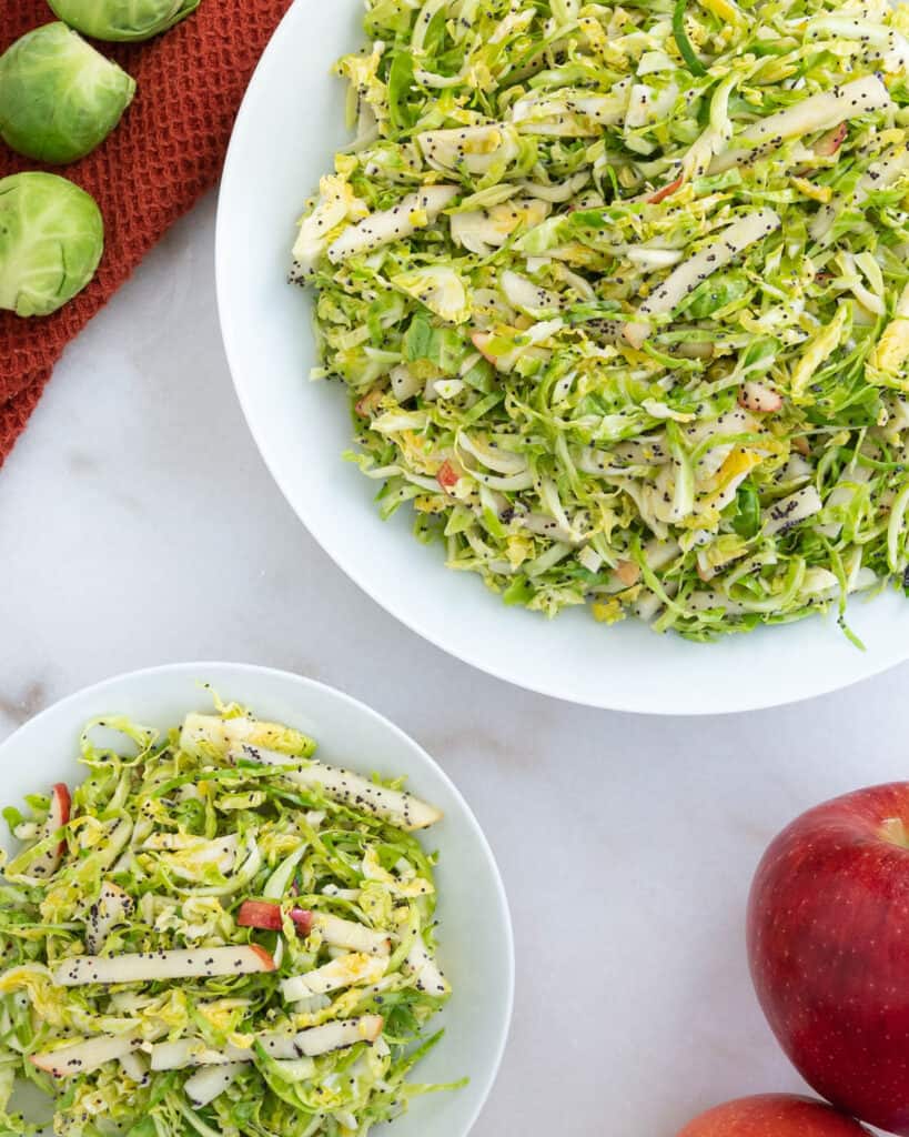 completed brussels sprouts slaw in a white bowl with brussels sprouts in the background