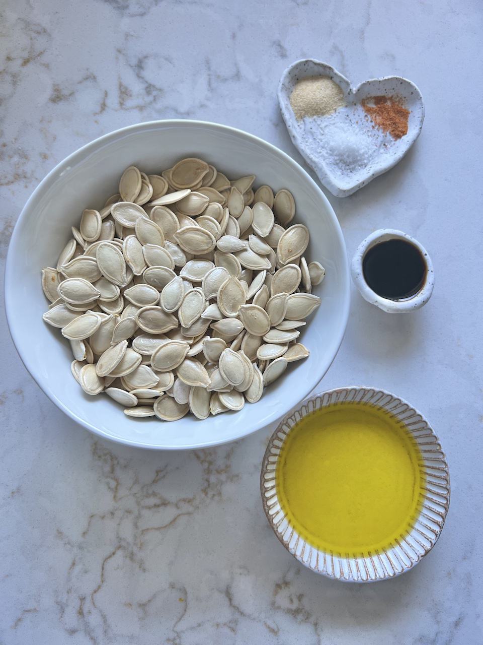 ingredients for roasted spicy pumpkin seeds measured out on a white surface