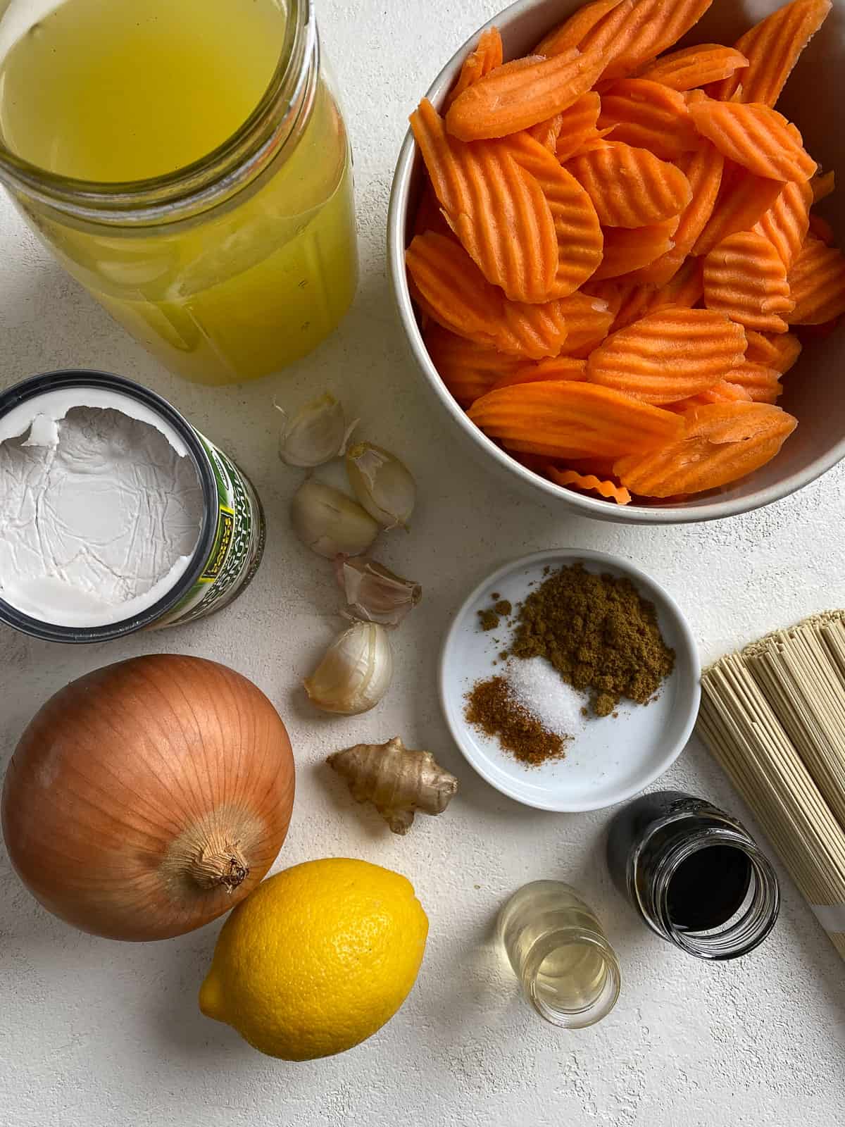 ingredients for Curried Carrot Soup with Noodles measured out against a white surface