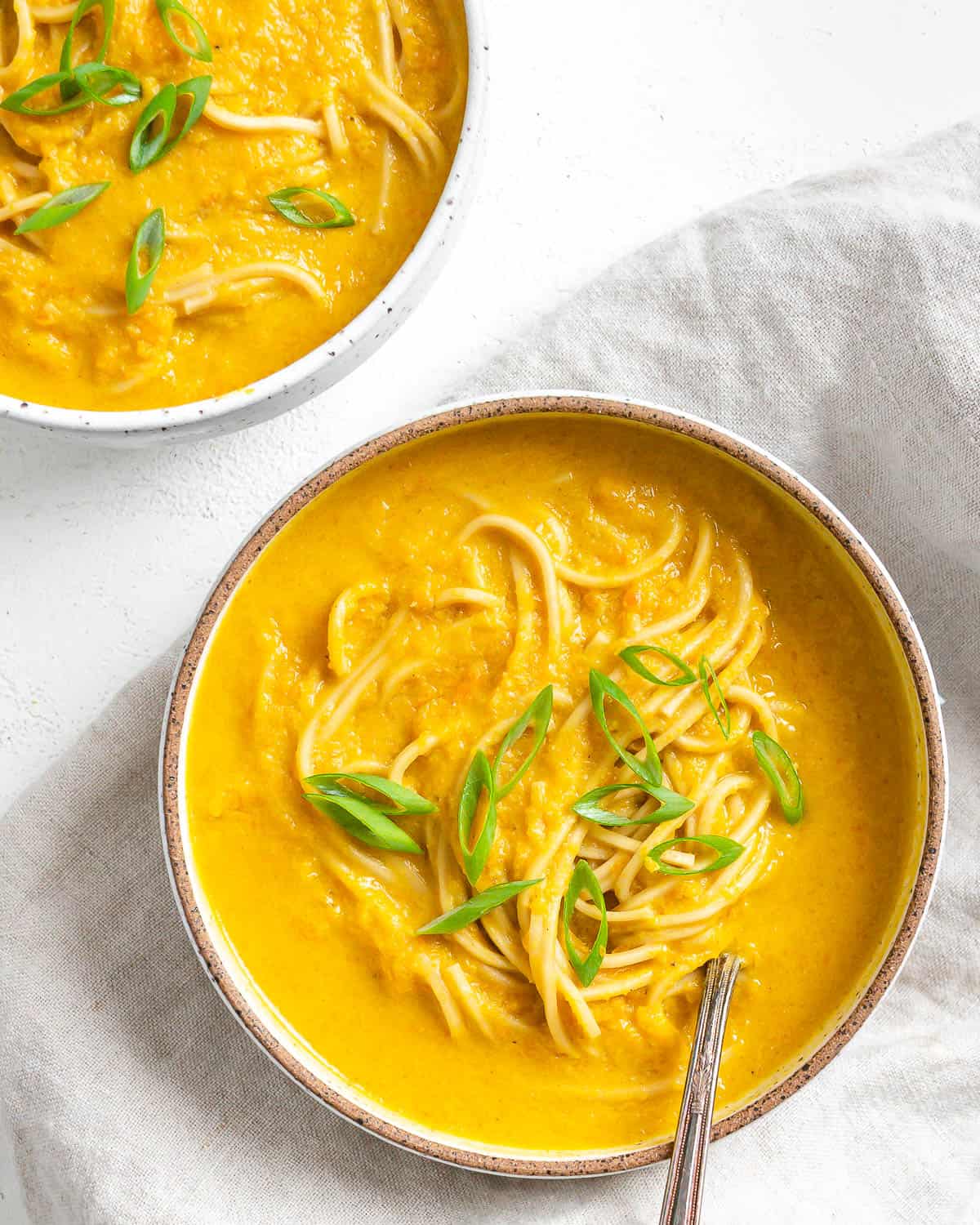 completed Curried Carrot Soup with Noodles against a white surface