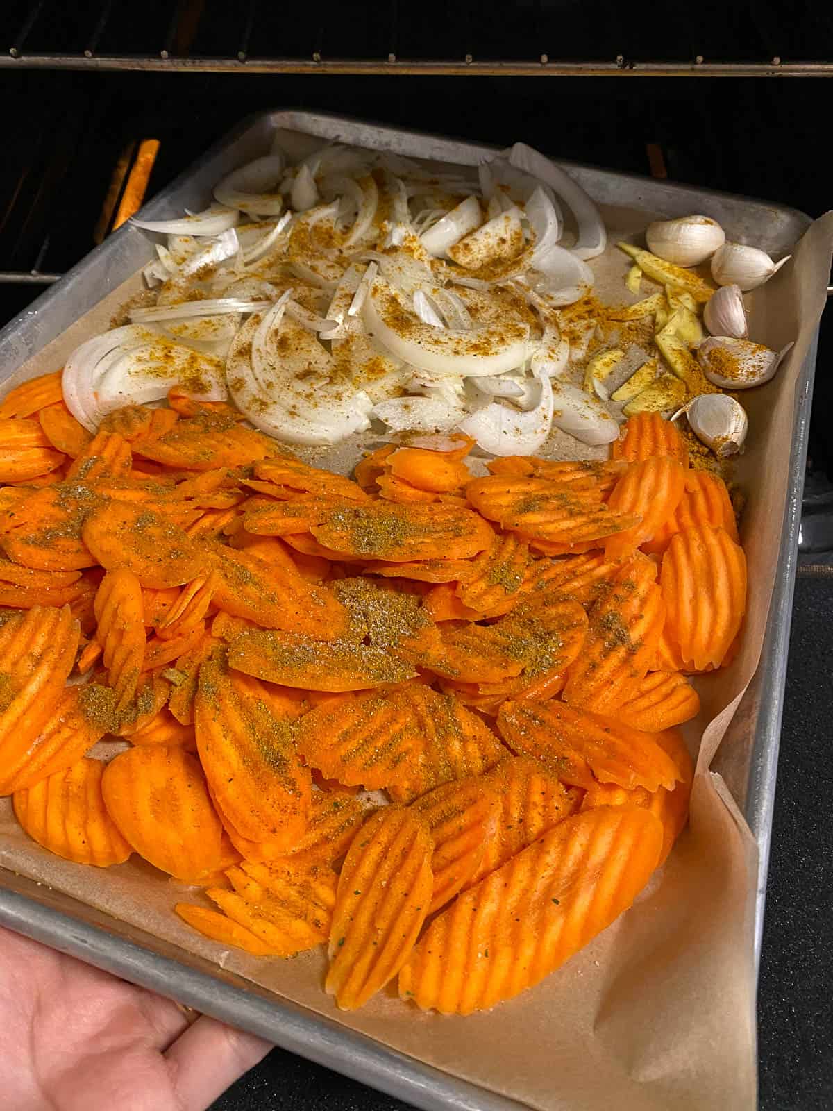 process of veggies for Curried Carrot Soup with Noodles in a baking pan being placed in an oven