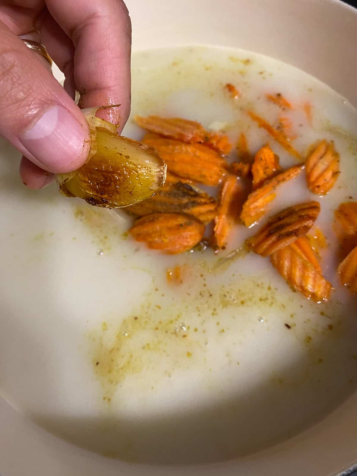 process of squeezing garlic from its papers into pan