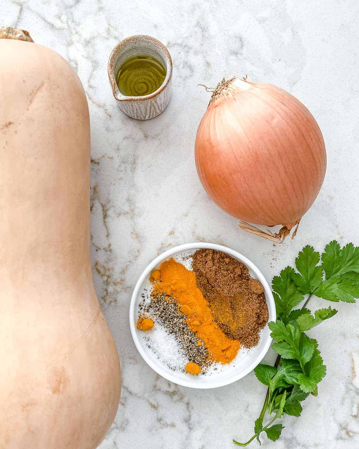 ingredients for Roasted Butternut Squash with Indian Spices and Caramelized Onions on a white marble surface