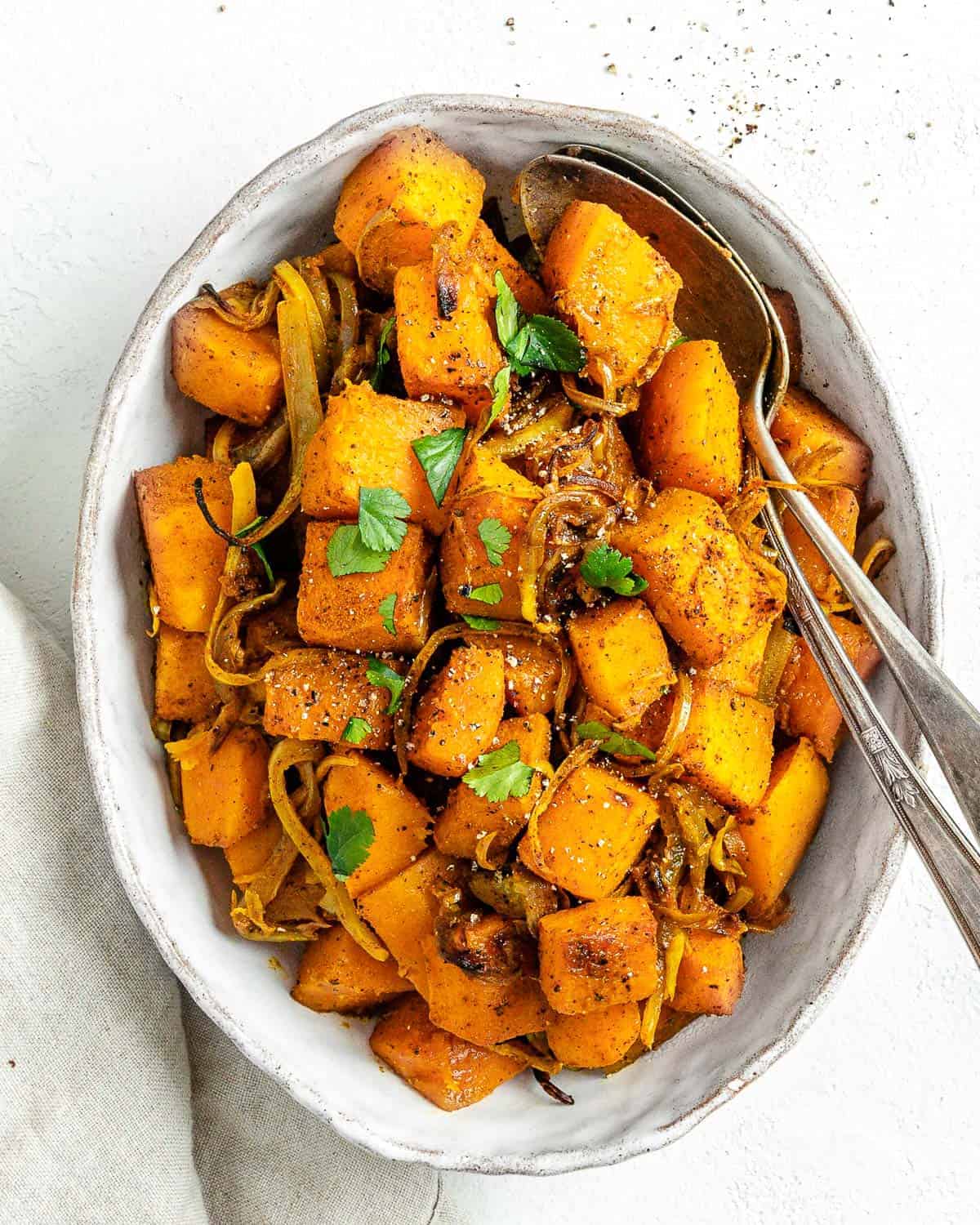 completed Roasted Butternut Squash with Indian Spices and Caramelized Onions in a serving tray against white background