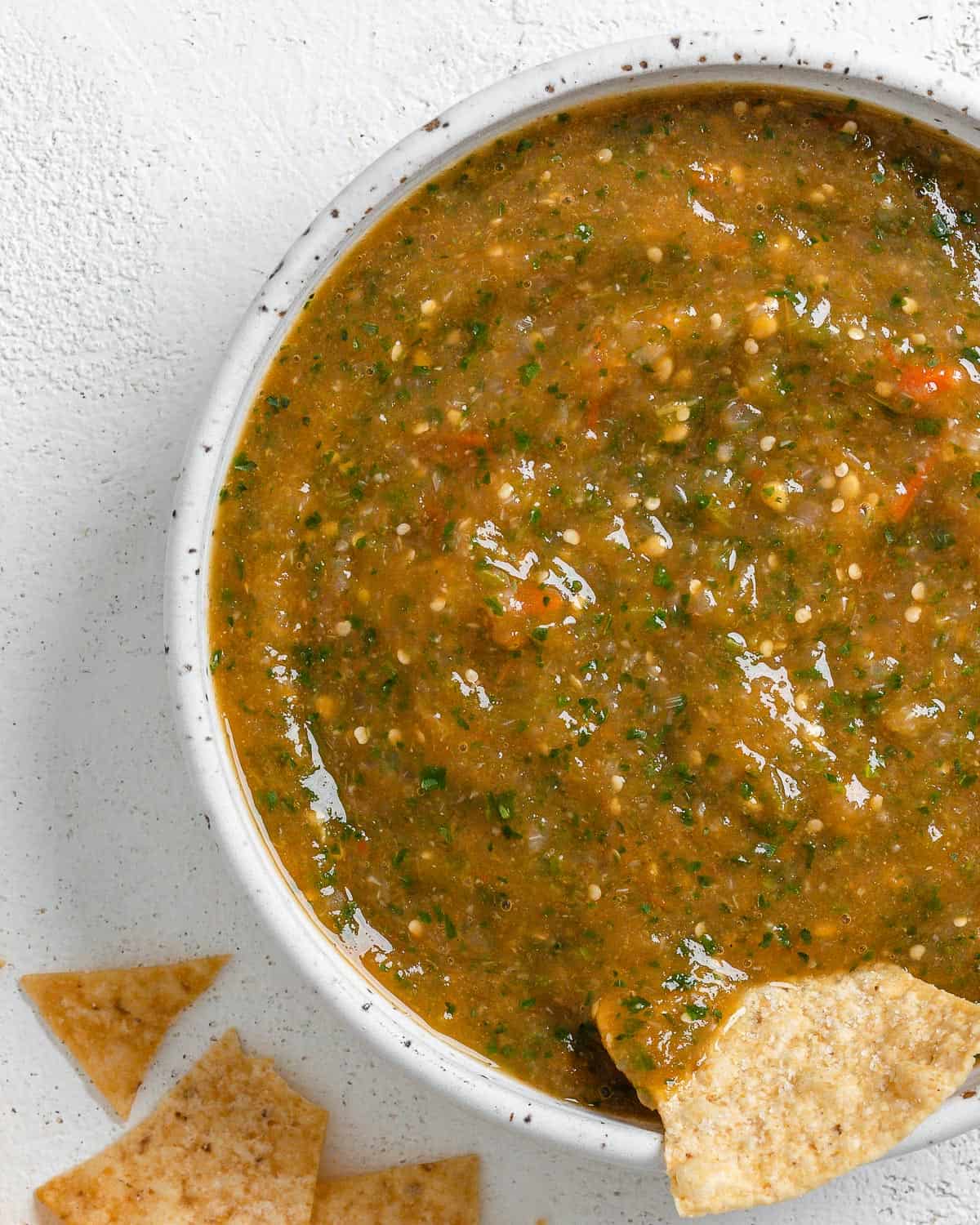 completed Stovetop Tomatillo Salsa in a bowl with a chip being dipped in it