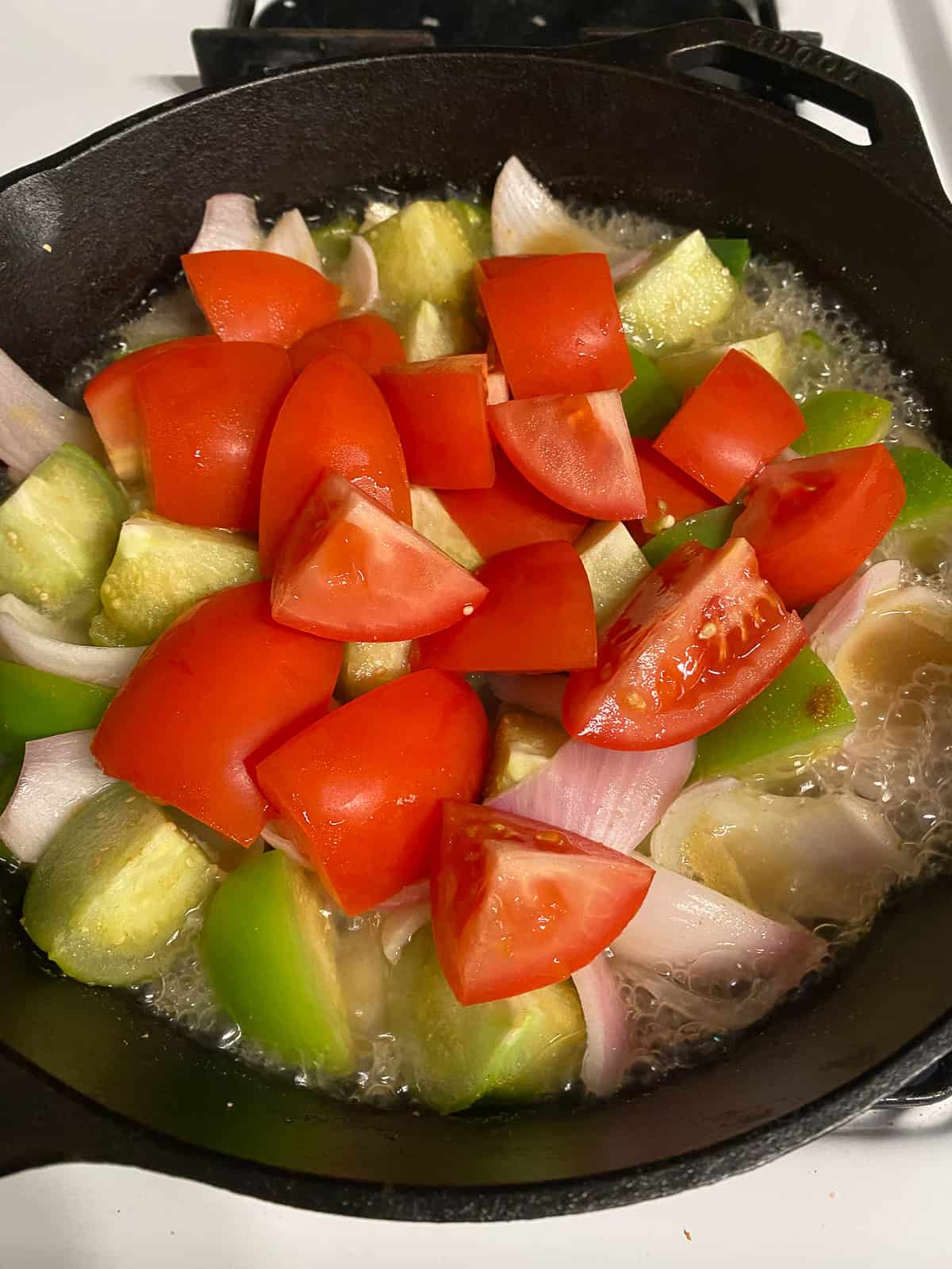 addition of tomatoes to pan of veggies