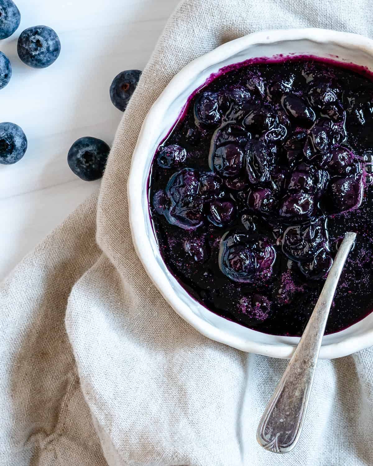 completed 2 Minute Blueberry Maple Syrup in a white bowl against a white surface and light towel