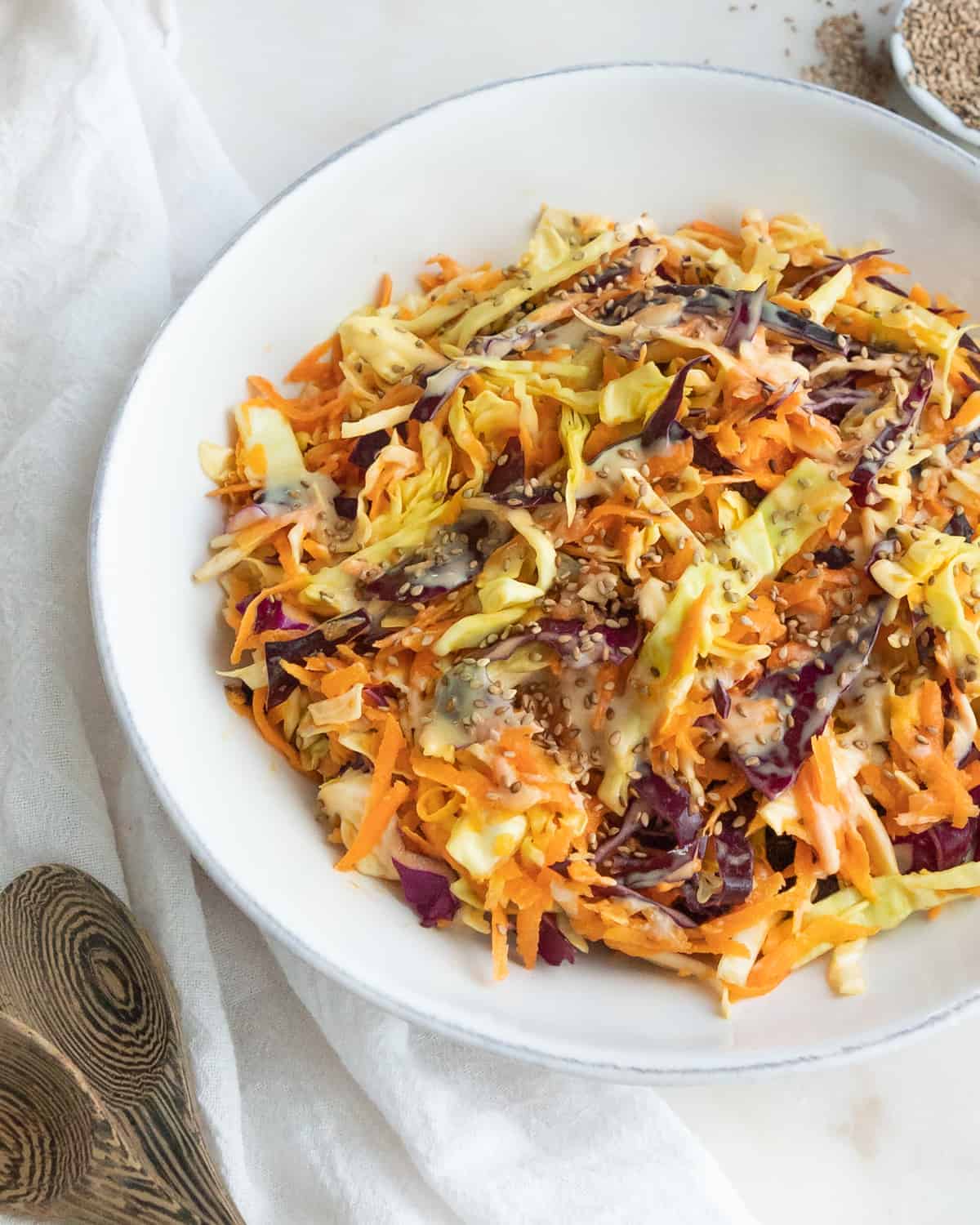 completed coleslaw in a white bowl against a white surface