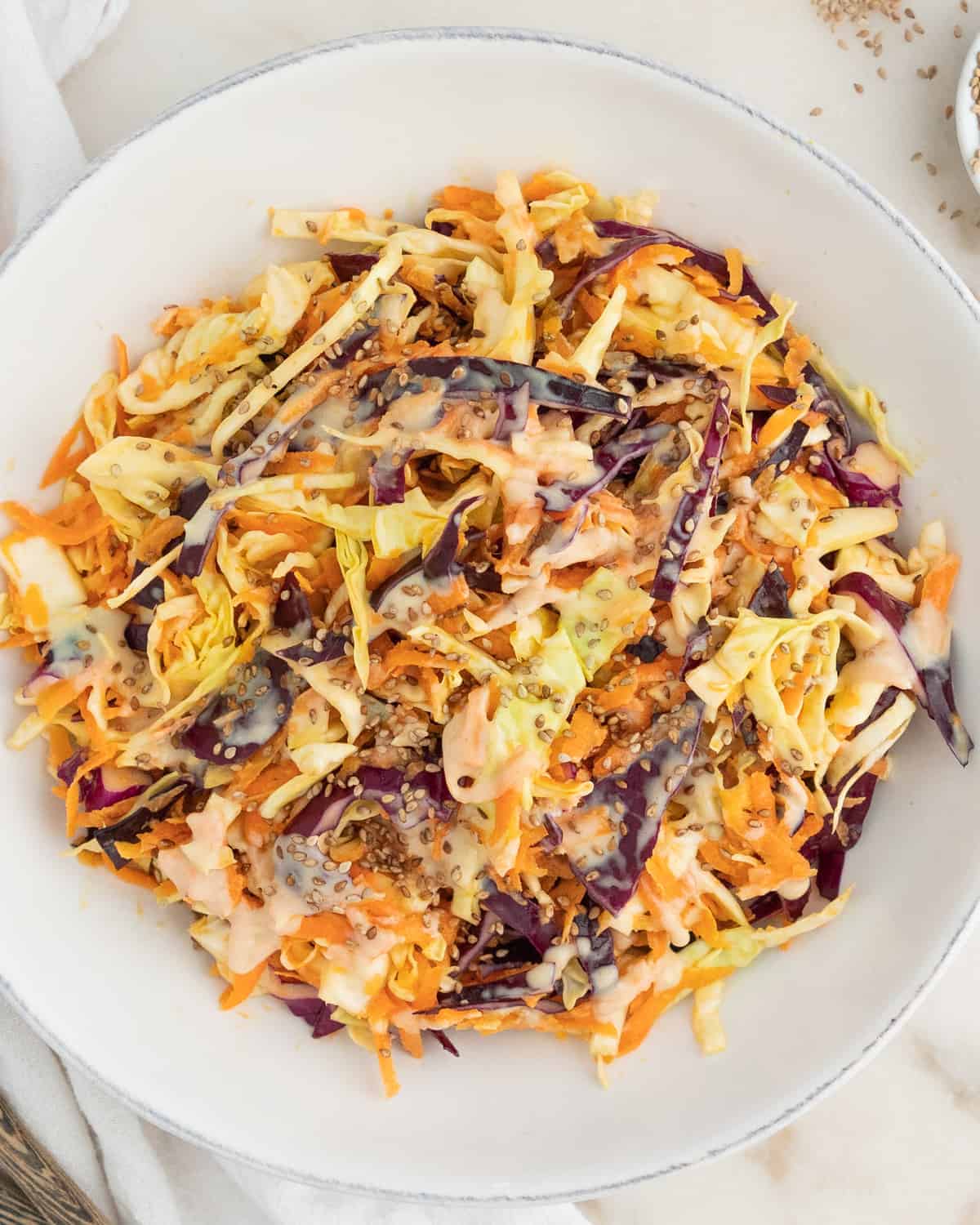 completed coleslaw in a white bowl against a white surface