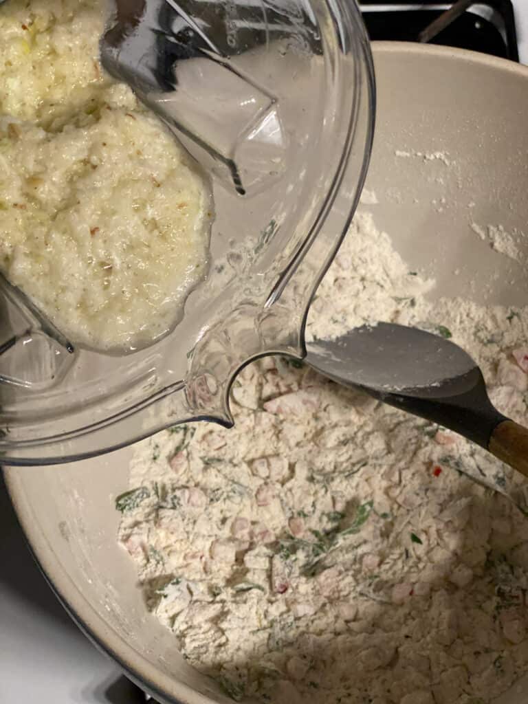 process shot of adding blended ingredients with dry ingredients in bowl