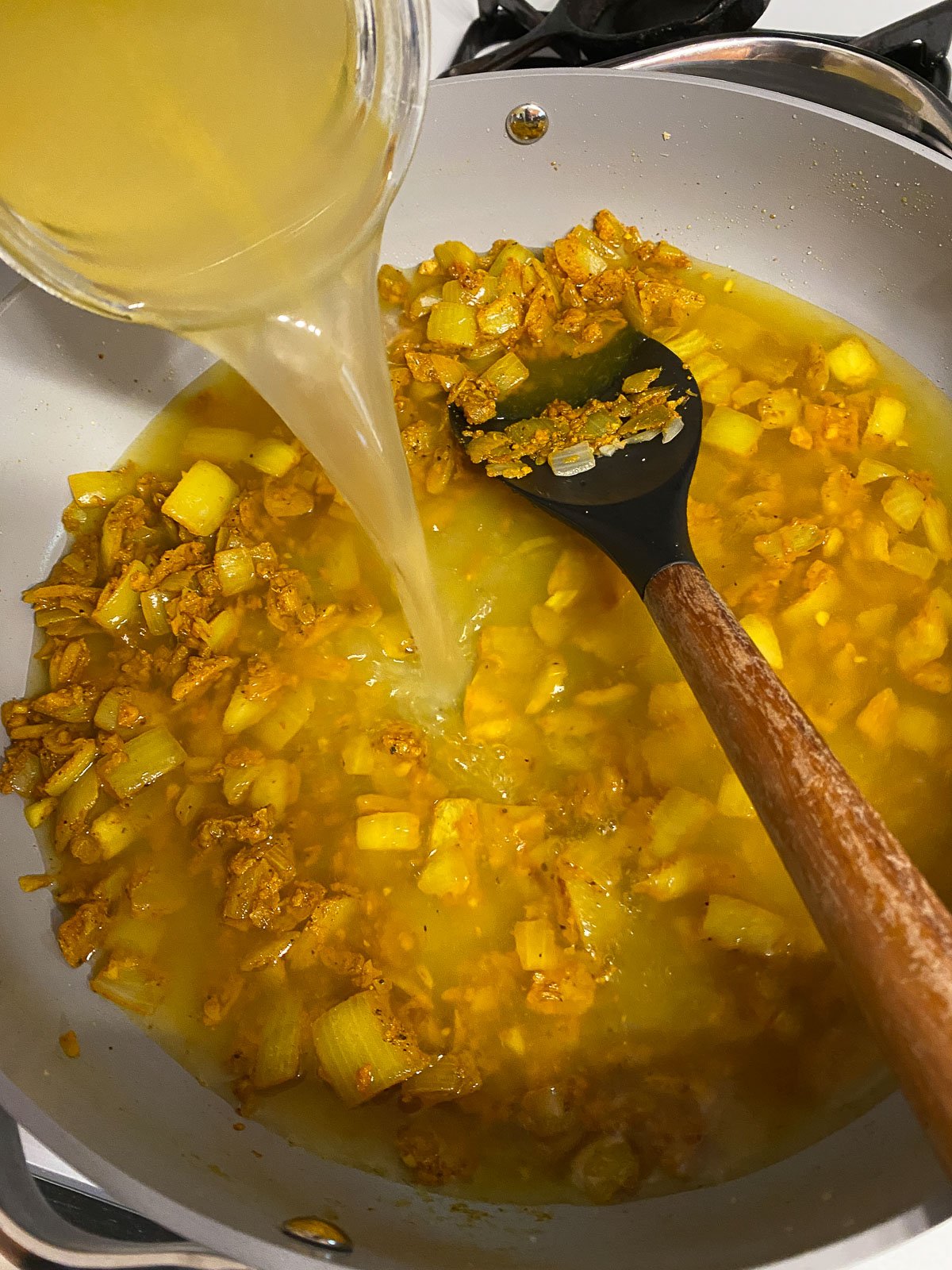 process shot of veggie broth added to pan