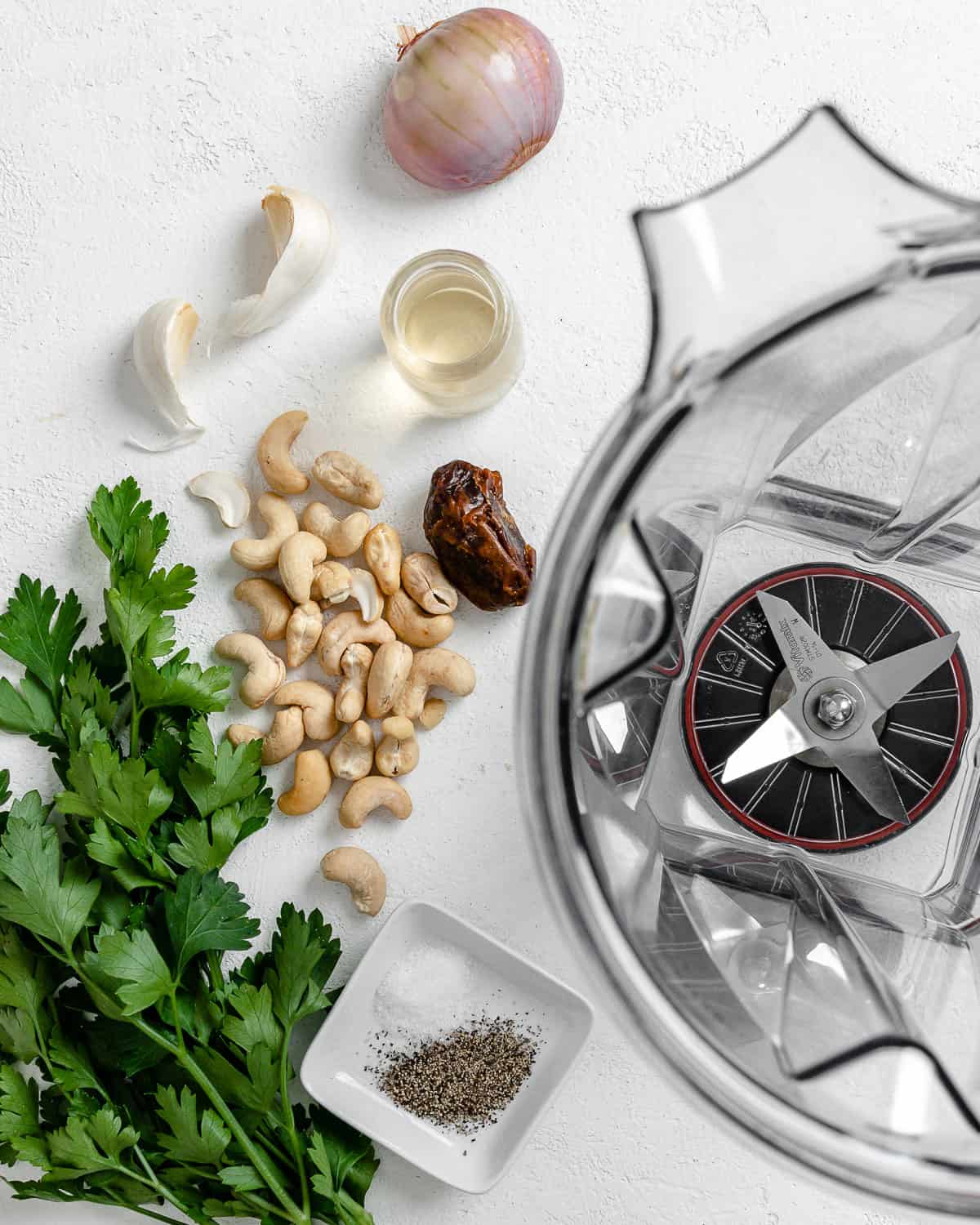 ingredients for Creamy Vegan Garlic Sauce alongside blender against a white background