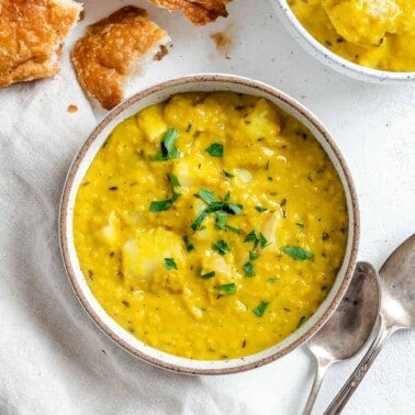 completed Lentil Potato Soup in a white bowl with ingredients in the background