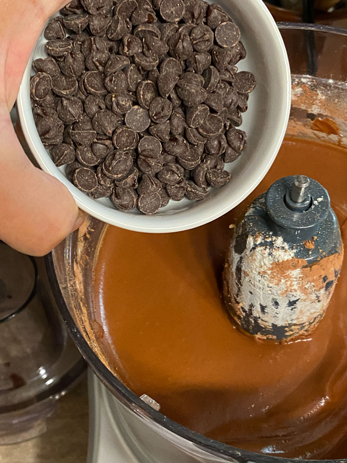 process of adding vegan chocolate chips into Sweet Potato Brownies mixture in blender