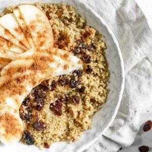 completed Breakfast Quinoa Apple Bowl in a white bowl with ingredients scattered in the background