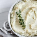 completed mashed cauliflower in a white dish against white background