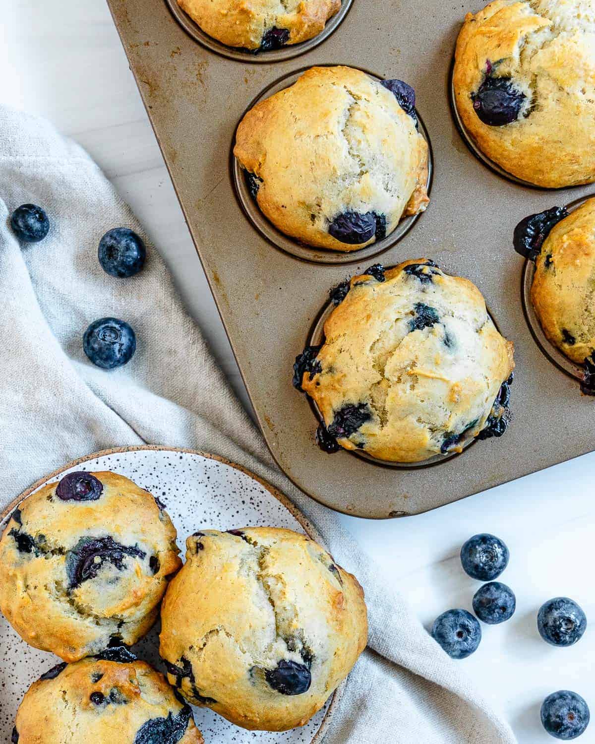 completed blueberry banana muffins in tin and plated against white surface