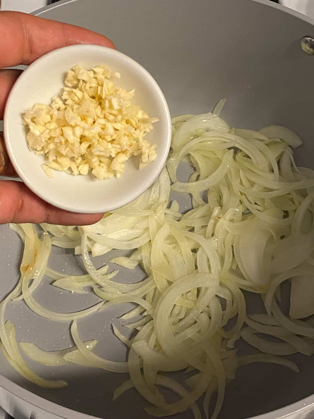 process of adding minced garlic to pan