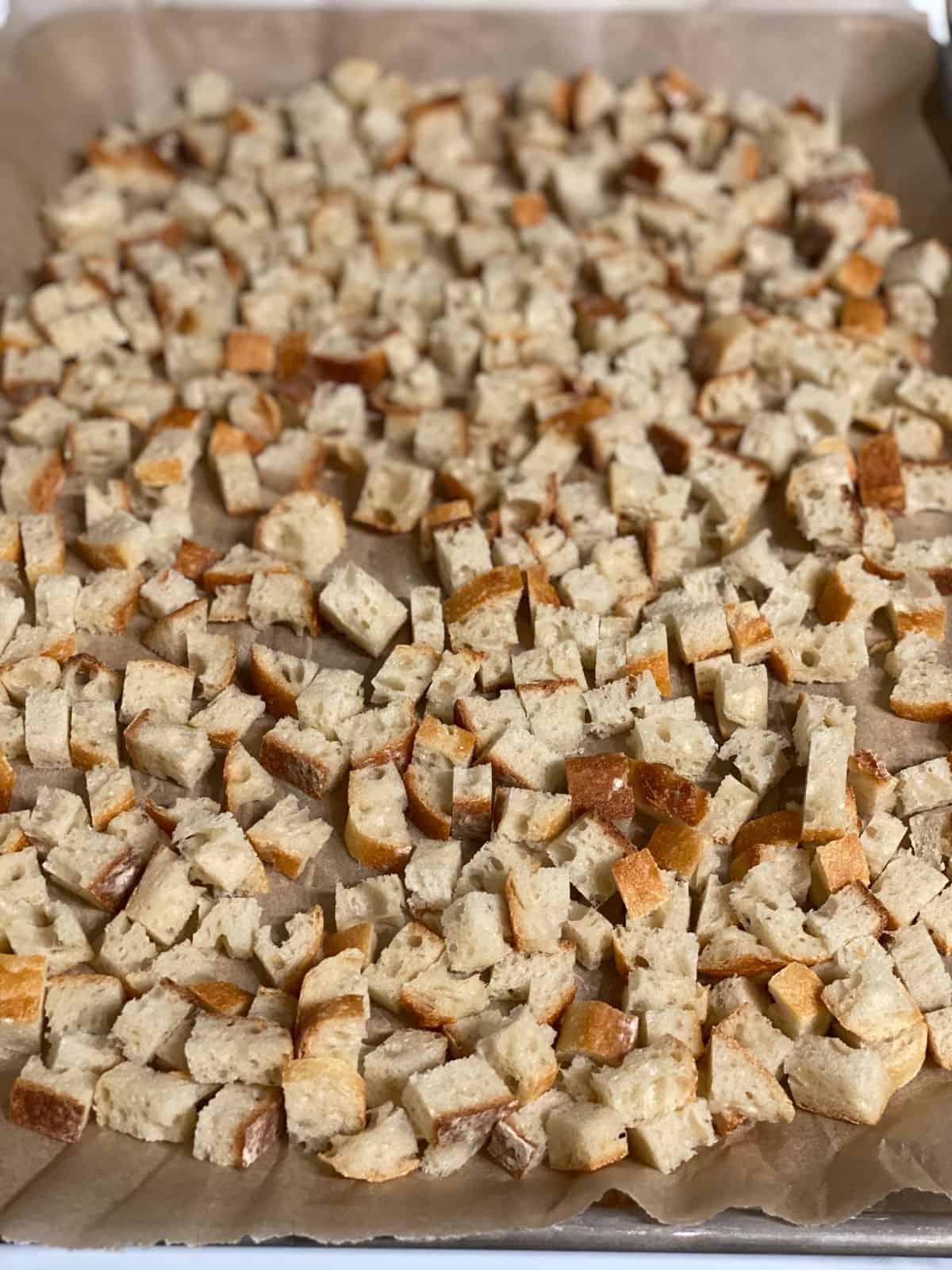 diced sourdough baguette spread out on a baking tray