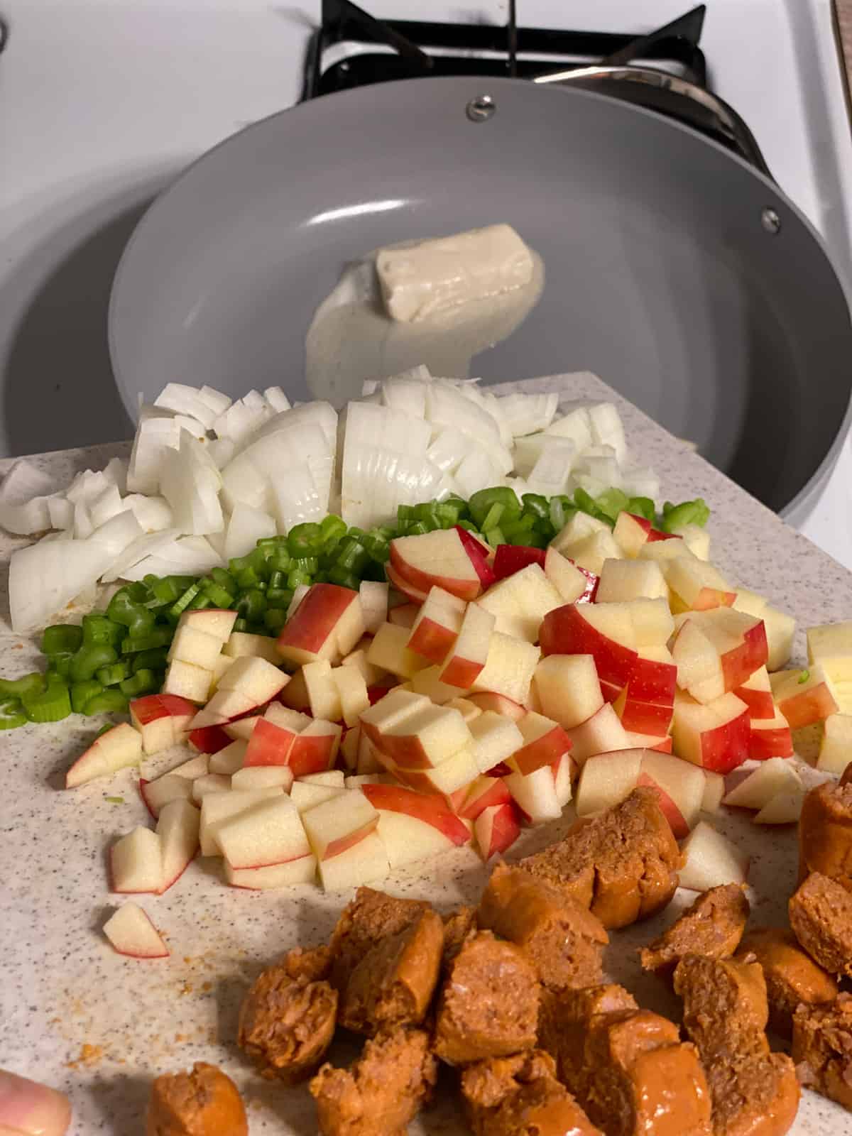 process of veggies and vegan sausage being added to pan