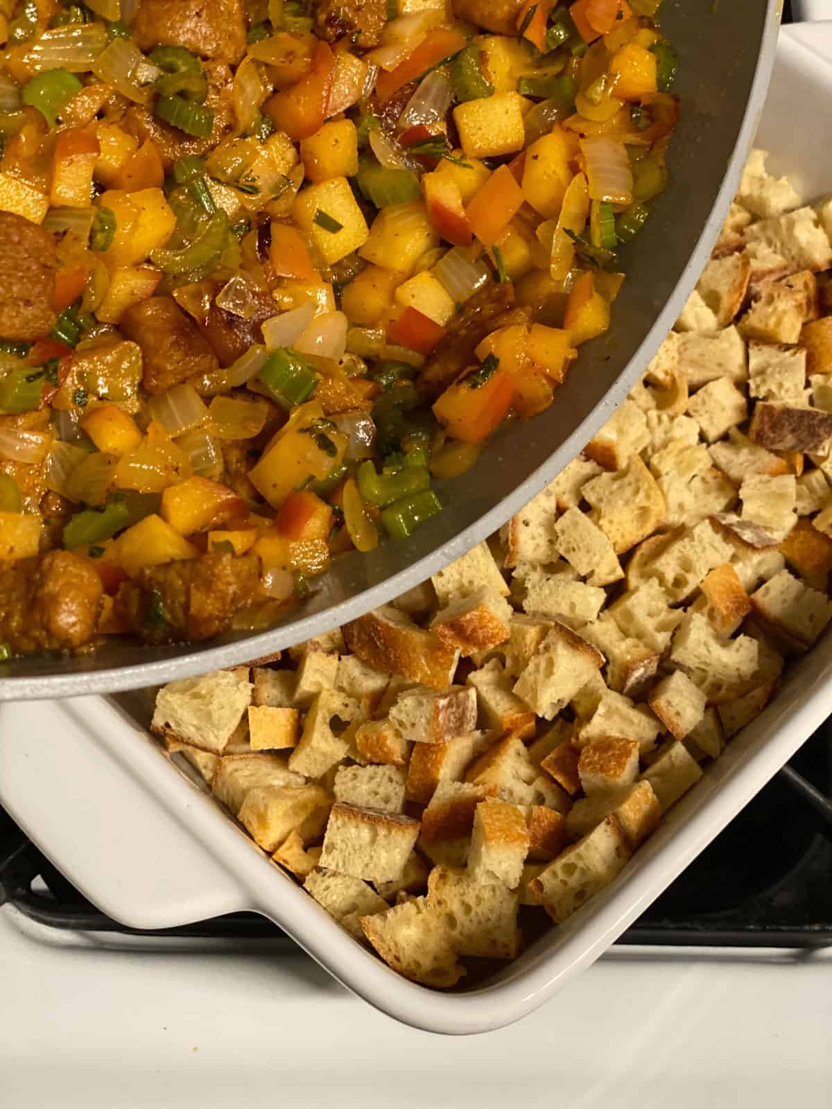 process shot of mixing cooked ingredients into pan of diced baguette