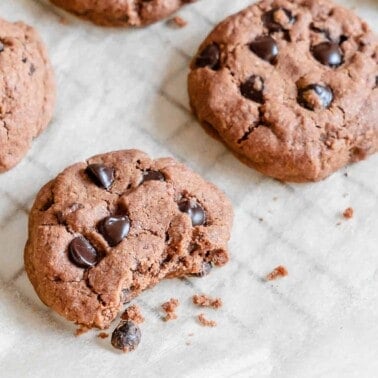 finished Chocolate Peppermint Chocolate Chip Cookies on parchment paper with one halved in the front