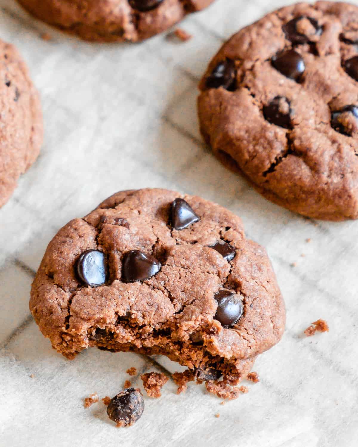 finished Chocolate Peppermint Chocolate Chip Cookies on parchment paper with one halved in the front