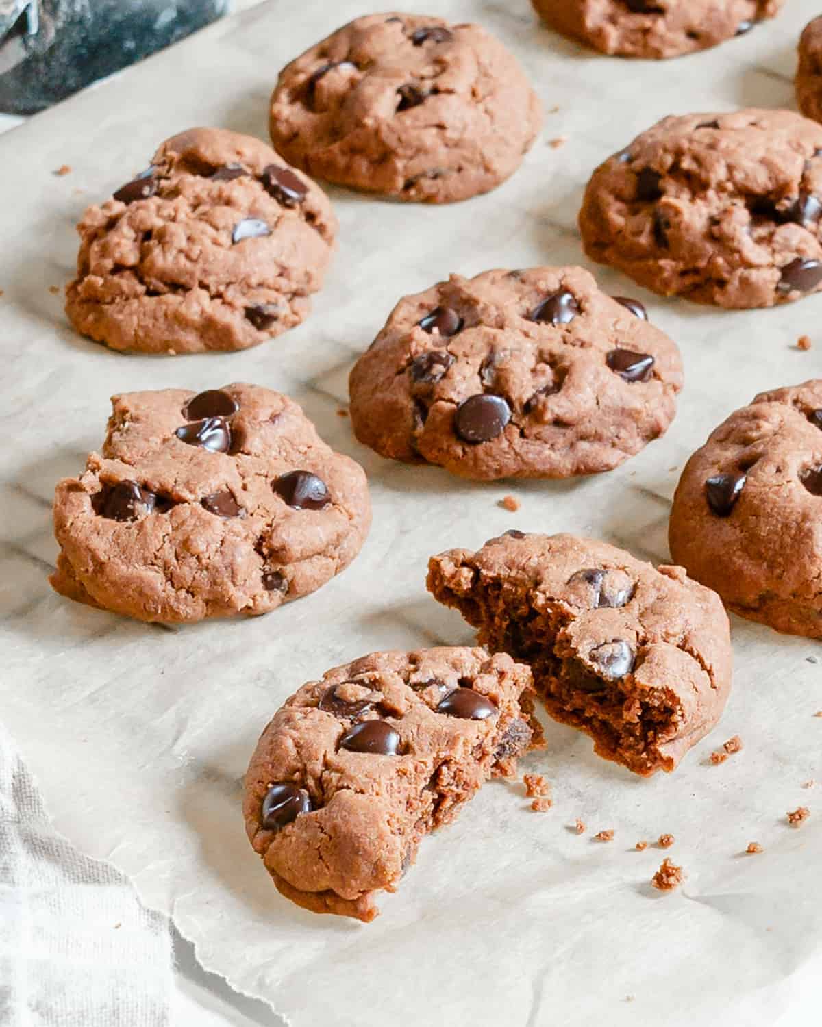 finished Chocolate Peppermint Chocolate Chip Cookies on parchment paper with one halved in the center