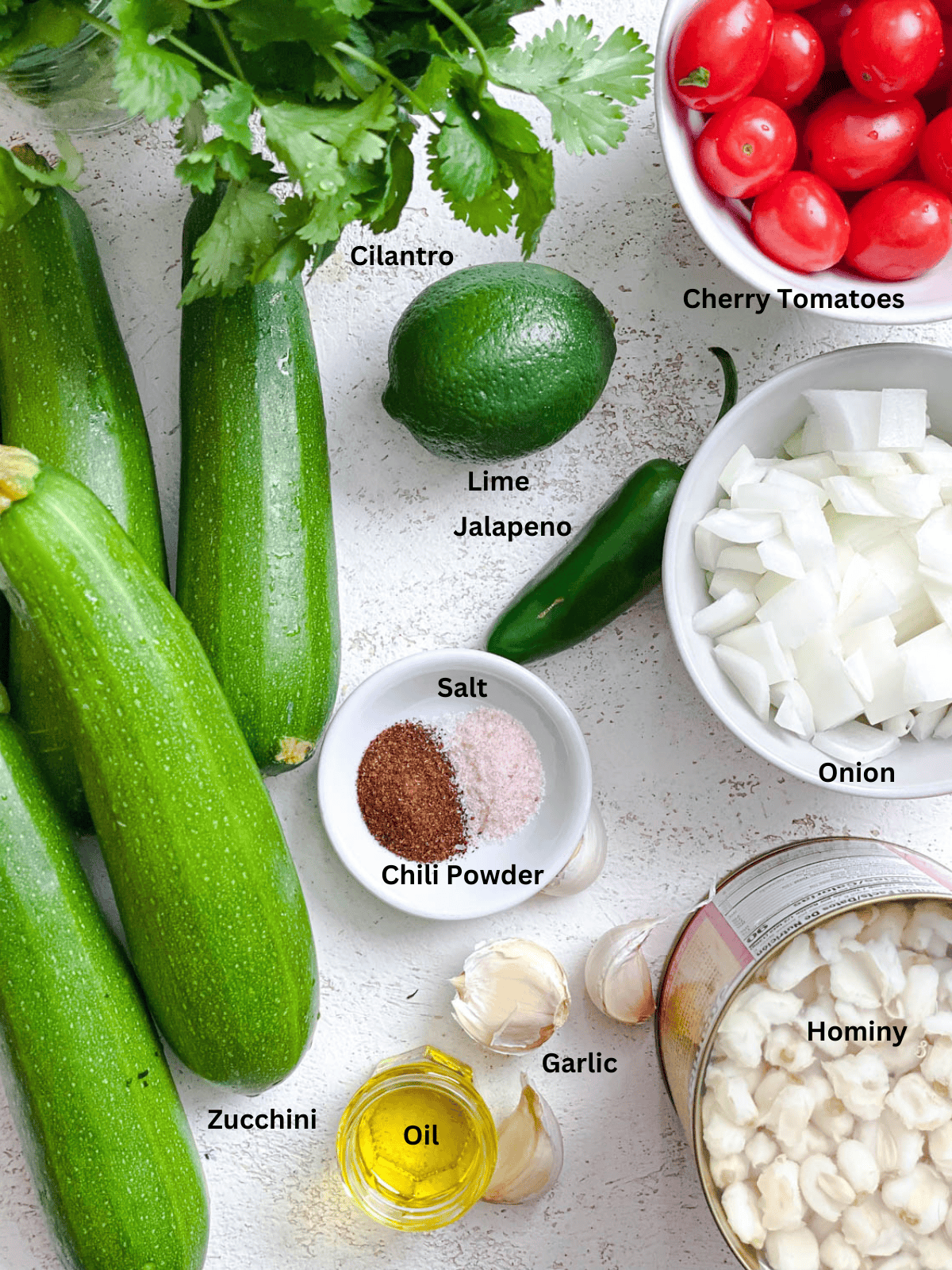 ingredients for Summer Zucchini and Hominy measured out on a white surface