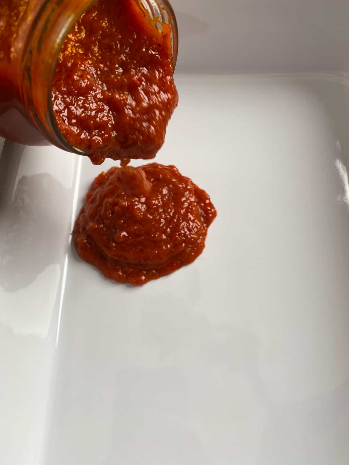 process of marinara sauce being added to white baking dish