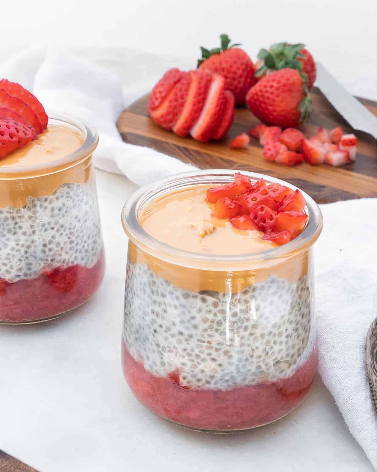 completed Healthy Chia Pudding in a glass jar with strawberries in the background