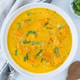 completed butternut squash lentil soup in a white bowl against a white background