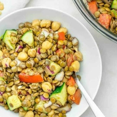 mediterranean lentil salad in a white bowl against a white background