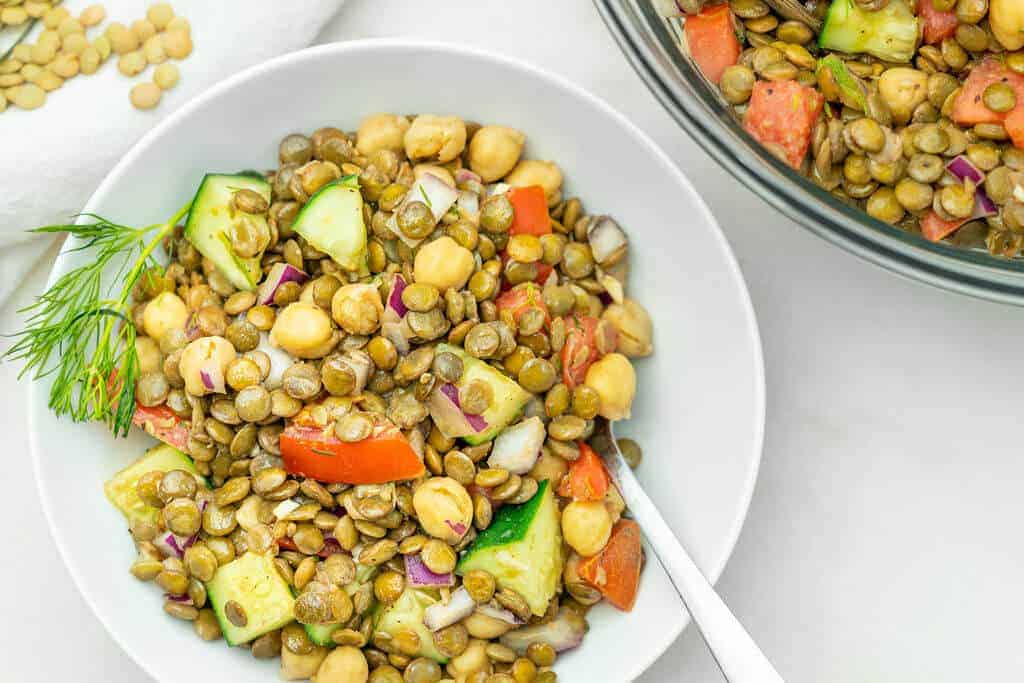 mediterranean lentil salad in a white bowl against a white background