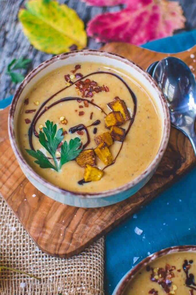 finished Pumpkin Soup in a white bowl with a cutting board and several towels in the background