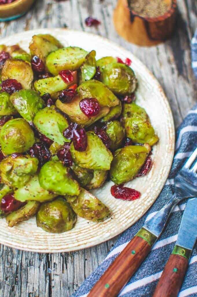 Roasted Brussel Sprouts in a white plate against a dark gray wood background