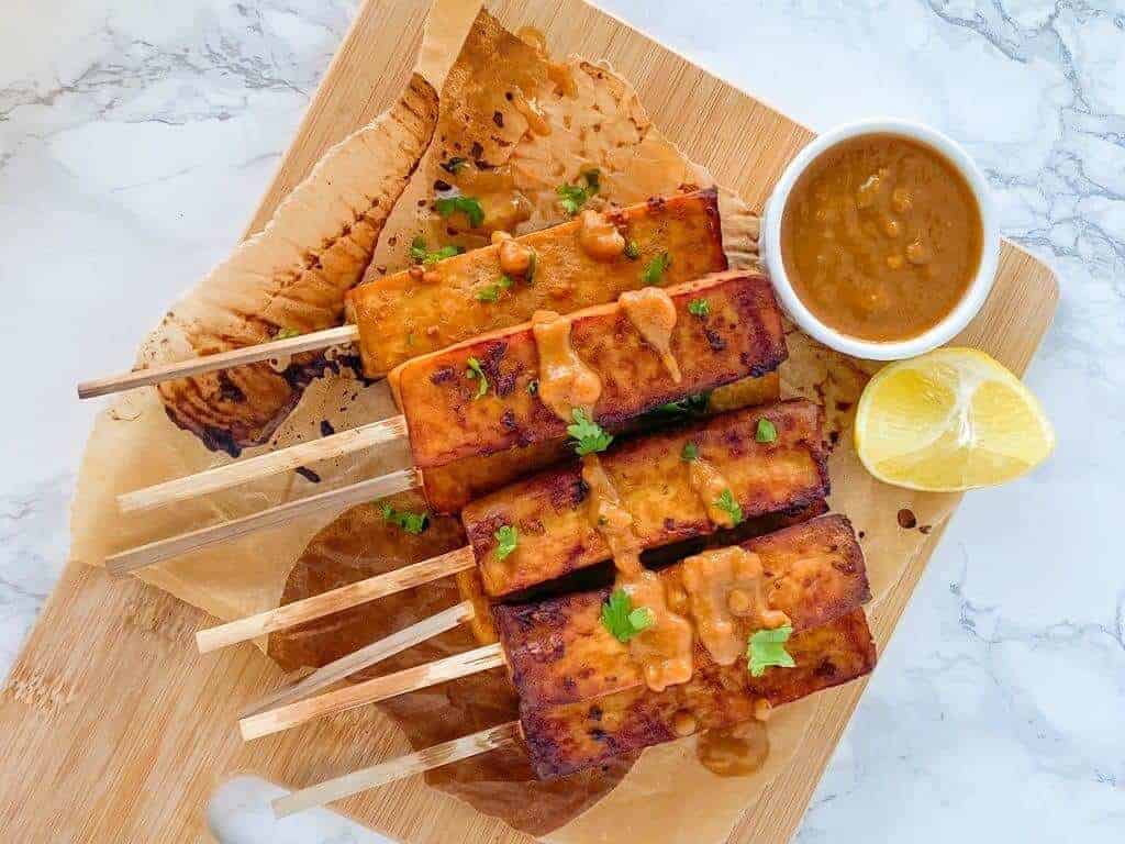 Oil-Free Tofu Satay with Peanut Sauce on a wooden board