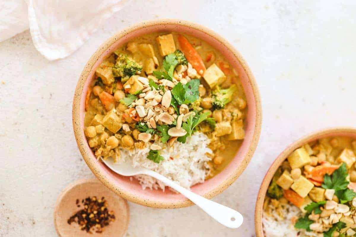 Peanut Curry in a pink bowl with a white spoon inside 