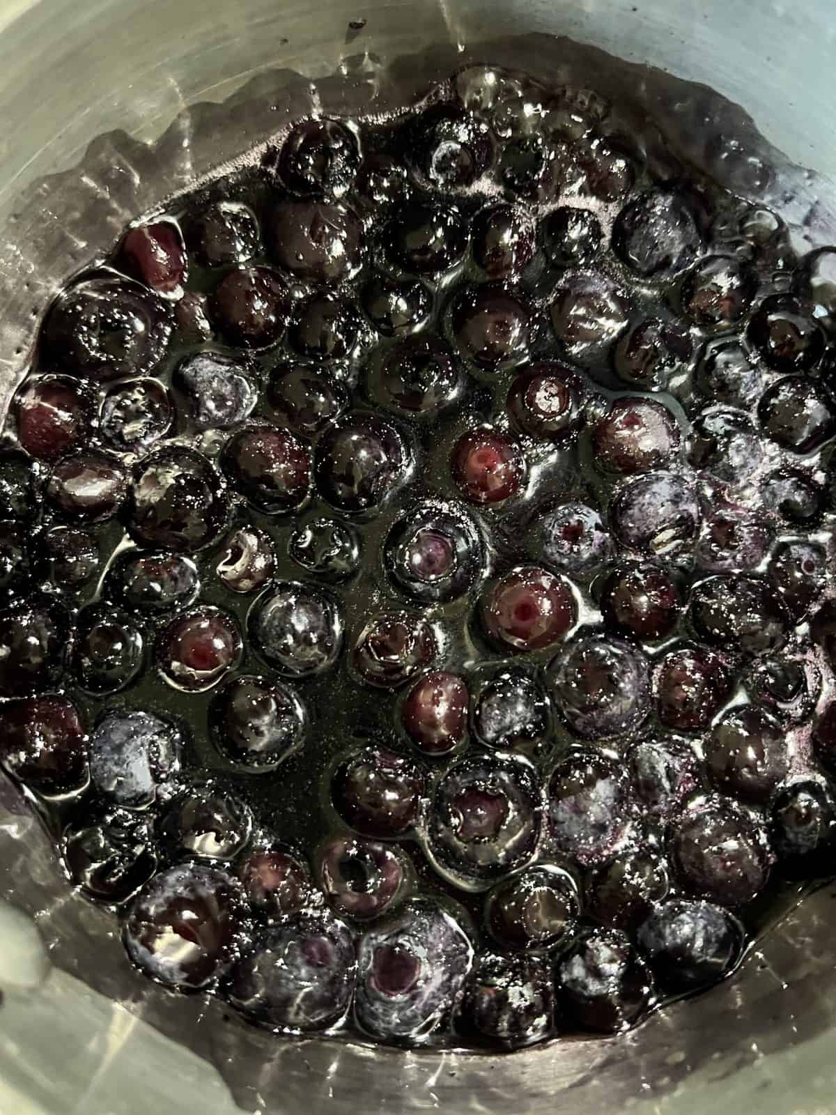 process of blueberries and maple syrup in a pot being cooked