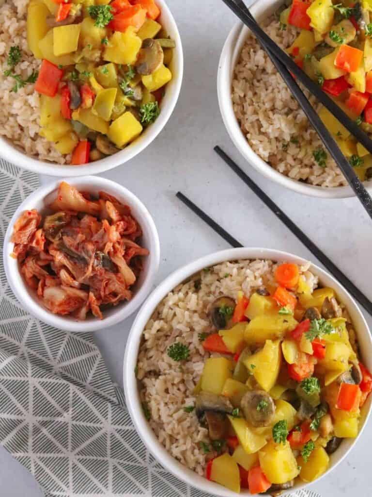 completed curry rice in two white bowls with two other white bowls in the background against a white background