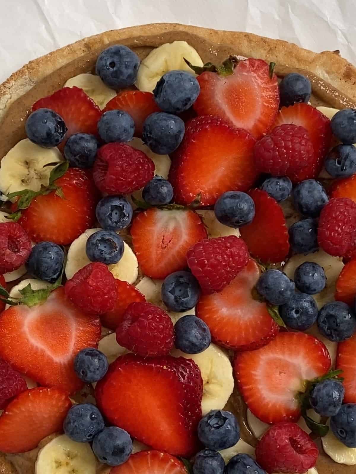 process of adding raspberries to fruit pizza