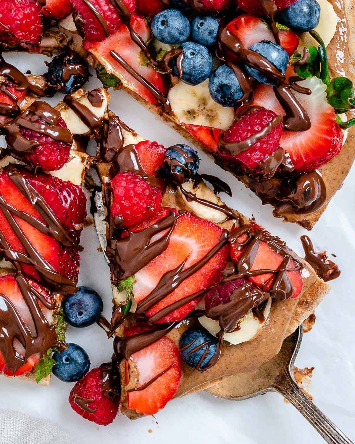 completed fruit pizza with one slice slightly shifted against a white background