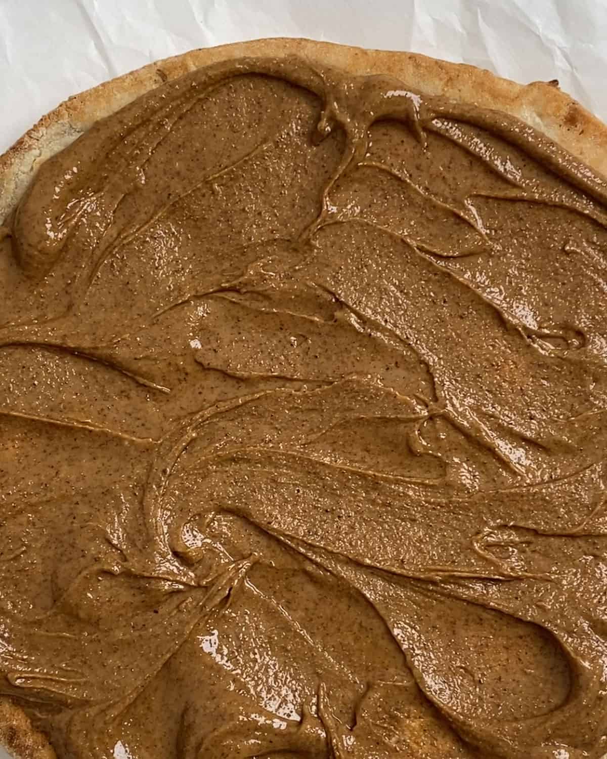 process of spreading nut butter on cauliflower crust