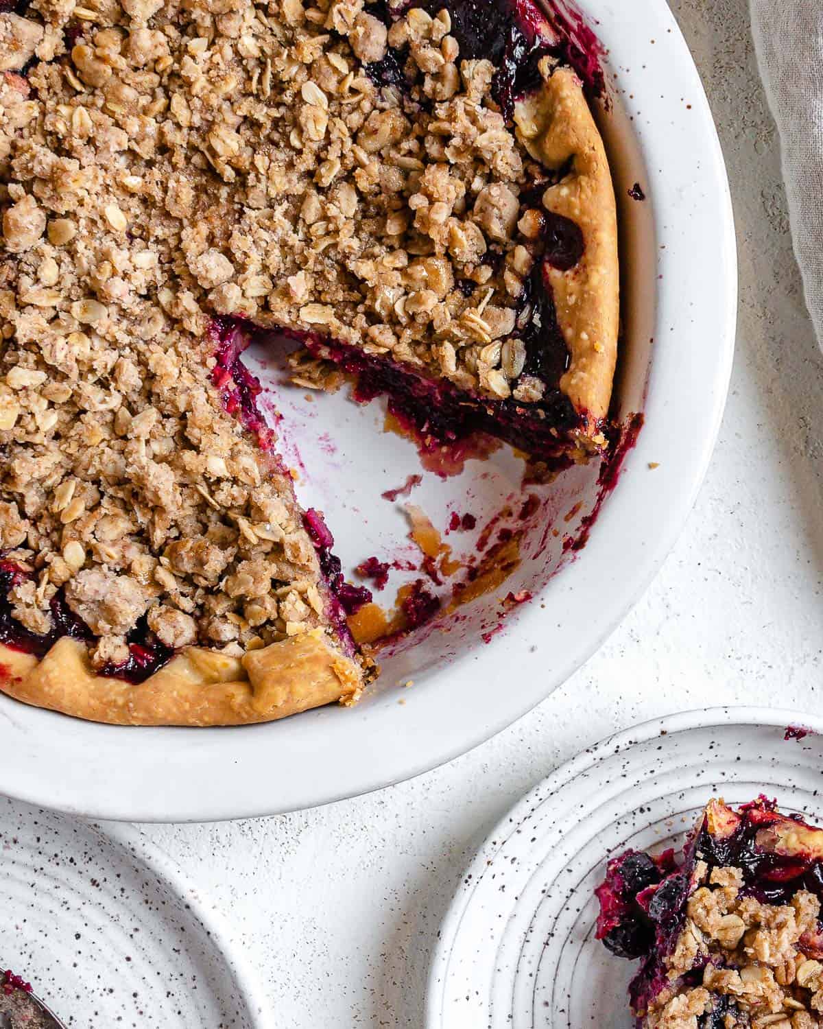 completed Mixed Berry Crumb Pie with a piece plated on a small white plate